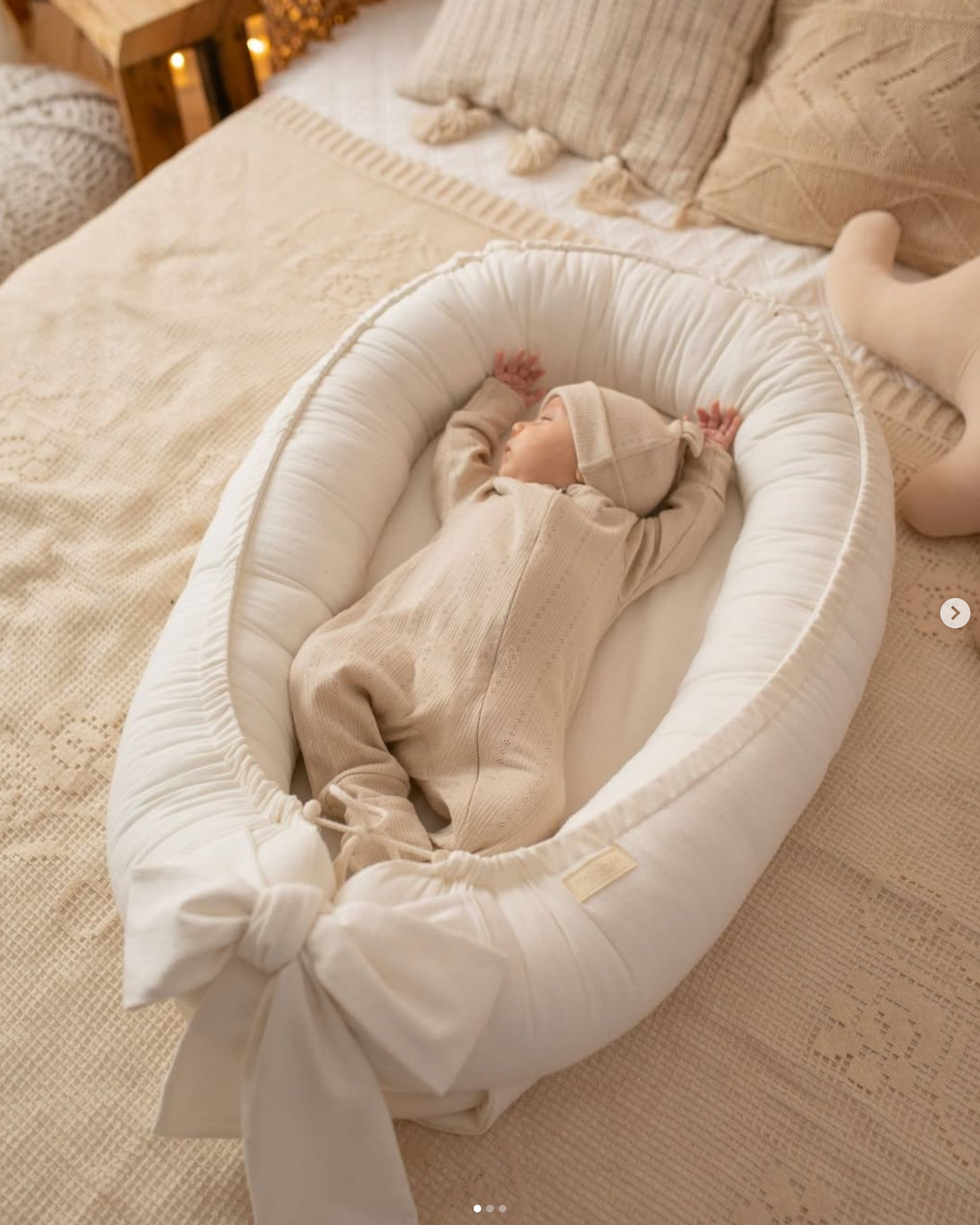 A baby dressed in beige laying in a beige pod