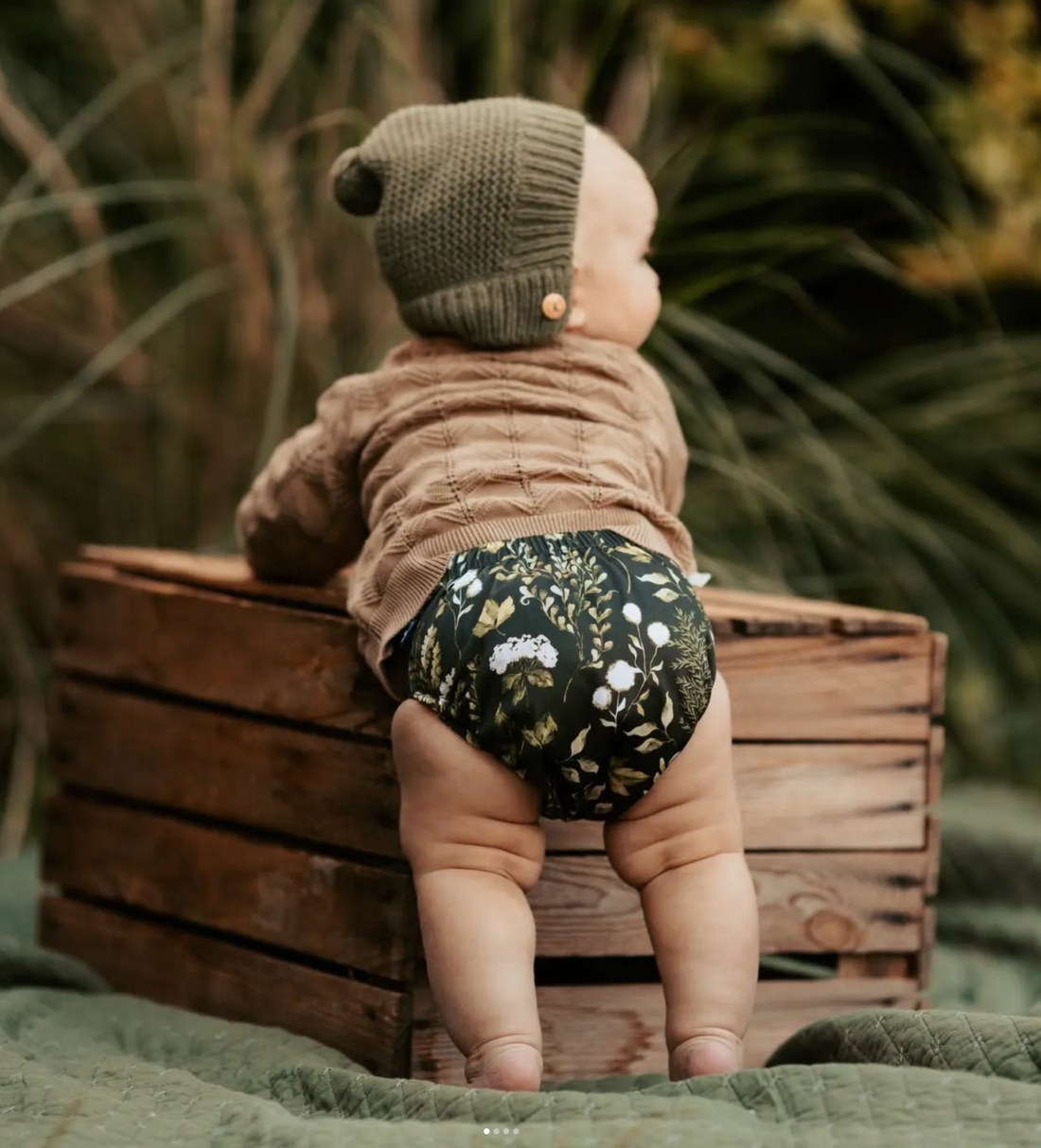 A baby in a resuable cloth diaper in a garden