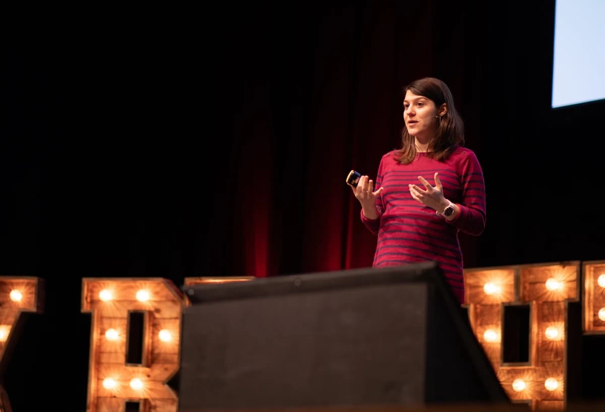 a photo of maggie in front of a large presentation slide